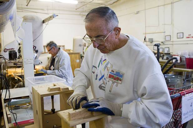 Bob Roeben burns the Toys 4 Smiles name on the bottom of a toy car at an assembly station in the Toys 4 Smiles workshop Monday, Dec. 8, 2014. The nonprofit organization started as a wood club in 2006 and will soon produce their 200,000th toy, said founder Rex Doty.