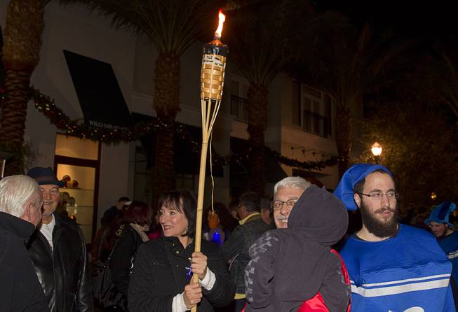 Gail Kessler, left, carries a torch through the crowd during a Hanukkah menorah lighting ceremony in The District in Henderson Thursday, Dec. 18, 2014. The event, celebrating the third night of Hanukkah, was organized by Chabad of Green Valley.