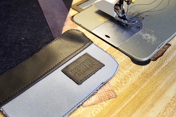 A piece of a The Revive Brand Co. backpack is shown by a sewing machine in Revive home office Thursday, Dec. 18, 2014.