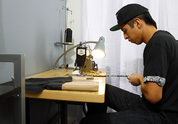 Cesar Santos, Revive research and development/production manager, forks on a backpack in the Revive home office Thursday, Dec. 18, 2014.