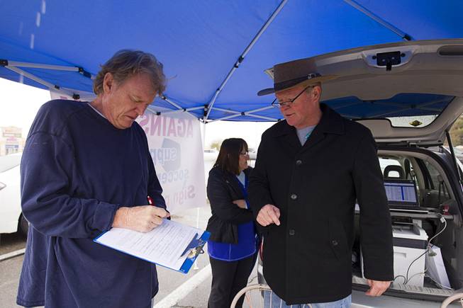 Las Vegas City Councilman Bob Beers, right, looks on as William Mallard signs a petition opposing spending taxpayer money on a downtown soccer stadium Sunday, Jan 11, 2015. Opponents needed 2,306 signatures to bring the project up for a referendum.