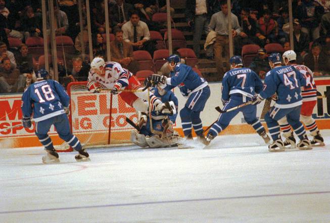 Brian Leetch of the New York Rangers goes airborne in front of Quebec Nordiques goalie Ron Hextall as he gets tripped by Quebec defenseman Kerry Huffman at New York's Madison Square Garden on Oct. 30, 1992. Nordiques players Mike Hough, Curtis Leschyshyn and Claude Lapointe and Rangers forward Mike Gartner watch the play. 