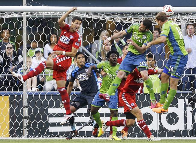 In this May 7, 2014, file photo, FC Dallas goalkeeper Raul Fernandez, second from left, and Dallas' Matt Hedges, left, watch as Seattle Sounders' Zach Scott (20) and Chad Marshall, right, go for a header as Sounders' Obafemi Martins, third from left, looks on during an MLS soccer match in Seattle. 