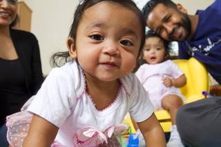 Mukhtar Omar Sharif Mukhtar and his Sylvia pose with their 10-month-old twin daughters Nahla, left, and Leelah at their home Thursday, March 12, 2015. Nahla moves in for a closer look at the camera. Mukhtar is director of this year's 