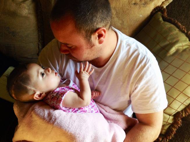 Kenny Yost holds his daughter Ily, then 6 months old, inside his mother's Henderson home in January. Ily's biological mother has been charged with child abuse and neglect in relation to injuries the infant suffered in November.