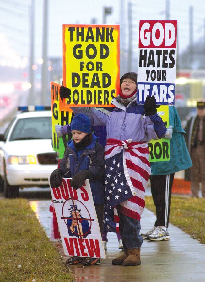 Margie Phelps, right, and Megan Phelps-Roper’s younger brother Gabriel, then 10, protest before the start of a memorial service for soldiers killed in combat in 2008. 