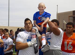 Players pick up Thaddeus Thatcher, 7, after he ran for a touchdown during practice at Bishop Gorman High School Wednesday, May 13, 2015. Thatcher, who has been diagnosed with Leukemia, became an honorary Gael for the day. Thatcher also learned he will learned he will be going to Walt Disney World, courtesy of Make-A-Wish Southern Nevada.