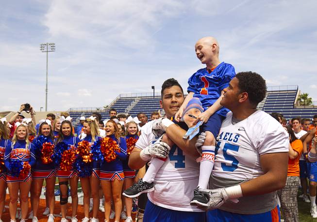 Thaddeus Thatcher, 7, is held up by players Julio Garcia and Jaron Caldwell at Bishop Gorman High School Wednesday, May 13, 2015. Thatcher, who has been diagnosed with Leukemia, became an honorary Gael for the day. Thatcher also learned he will learned he will be going to Walt Disney World, courtesy of Make-A-Wish Southern Nevada.