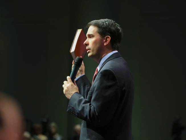 Wisconsin Gov. Scott Walker holds up a devotional while speaking at the Iowa Faith & Freedom 15th Annual Spring Kick Off, in Waukee, Iowa, Saturday, April 25, 2015.