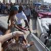 Fans take photographs of singer Rihanna as she gets on an American classic car after a photo shoot with photographer Annie Leibovitz at a building on the Malecon on Friday, May 29, 2015, in Havana, Cuba.