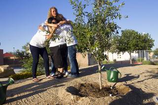 Family and friends of Joseph Wilcox embrace by a tree planted in memory of Wilcox in Walnut Park, adjacent to Metro Police Northeast Area Command, Monday, June 8, 2015. Wilcox was killed on June 8, 2014 while trying to stop two armed assailants that ambushed and killed Metro Police Officers Alyn Beck and Igor Soldo.