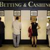 In this June 8, 2013, file photo, people stand at a betting and cashing window at Belmont Park in Elmont, N.Y., before the Belmont Stakes. 
