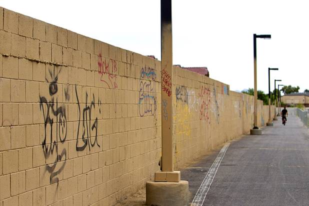 A cyclist rides by a wall covered in graffiti along the Las Vegas Wash channel near Pecos Road and Lake Mead Boulevard Tuesday, June 9, 2015.