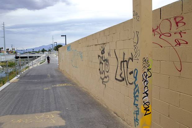 A cyclist rides by a wall covered in graffiti along the Las Vegas Wash channel near Pecos Road and Lake Mead Boulevard Tuesday, June 9, 2015.