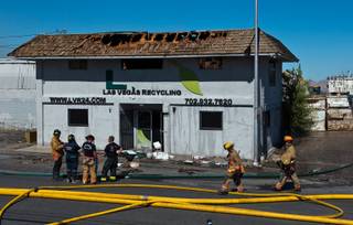 Firefighters gather outside of the Las Vegas Recycling building which was severely damaged by fire on Tuesday, June 16, 2015.