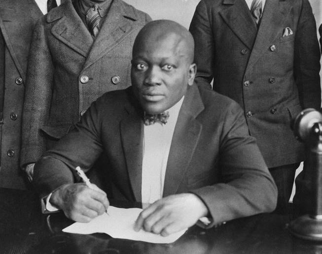 Boxer Jack Johnson is shown signing contracts in this undated photo.