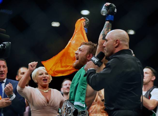 Interim featherweight title fight Conor McGregor, next to Joe Rogan, celebrates his win with his parents Margaret and Tony after defeating Chad Mendes in their UFC189 fight at the MGM Grand Garden Arena on Saturday, July 11, 2015.