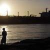 In this July 21, 2015 file photo, an oil tanker passes a fisherman as it enters a channel near Port Aransas, Texas, heading for the Port of Corpus Christi. 