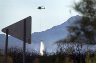 A helicopter drops water on the Willow Fire in Mohave Valley, Ariz. Monday, Aug. 10, 2015. Eleven homes are reported to have been destroyed in the blaze.