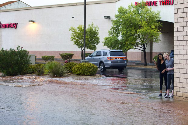 Women take video of storm runoff at Whitney Ranch Drive near Sunset Road during a thunderstorm in Henderson, Aug. 13, 2015.