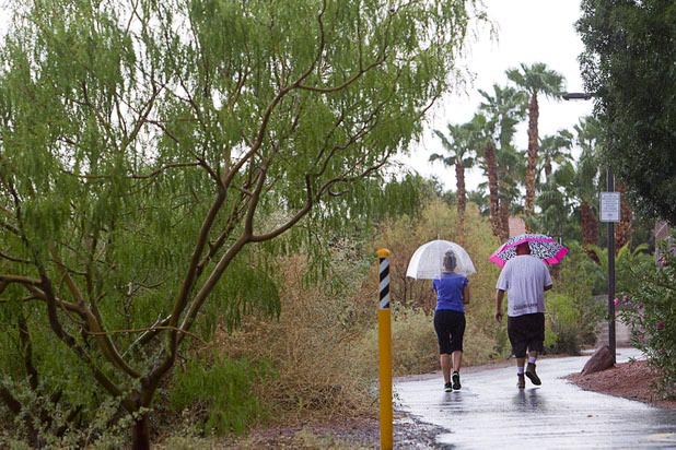 A couple walks on the Pitman Wash trail during a thunderstorm in Henderson, Aug. 13, 2015.