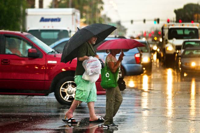 Pedestrians walk along South Eastern Avenue in an unsuccessful attempt to avoid getting wet during a heavy rainstorm moving across the Las Vegas Valley on Thursday, August 13, 2015.