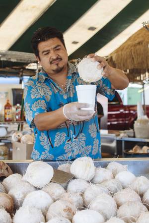 A merchant provides fresh coconut juice to customers at Broadacres Marketplace in Las Vegas, Nev. on Aug. 16, 2015.