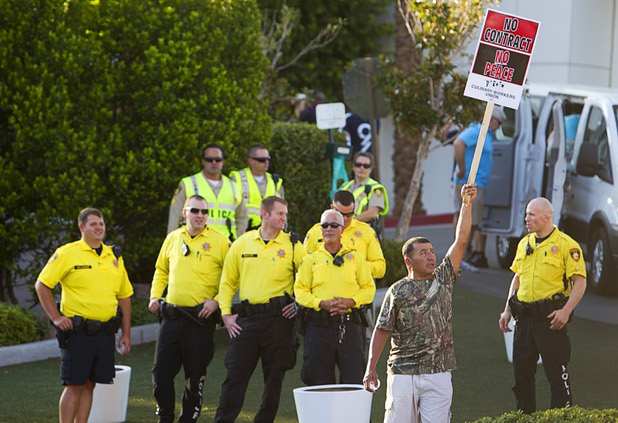 A man holds up a sign as Metro Police officers look on during a protest organized by the Culinary Workers Union, Local 226, near the Trump International Hotel Las Vegas Friday, Aug. 21, 2015. The Trump International Hotel workers are not unionized. STEVE MARCUS