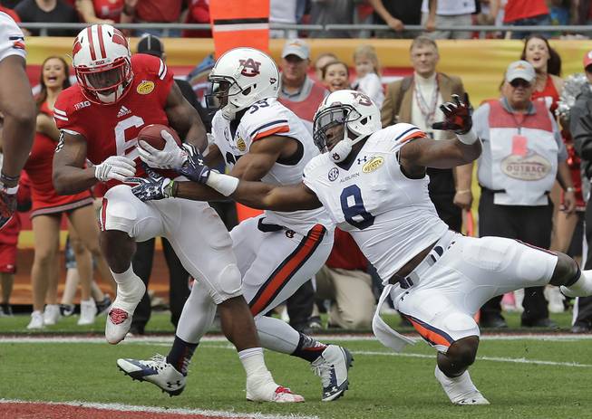 Wisconsin running back Corey Clement (6) drags Auburn defensive back Joe Turner (35) and linebacker Cassanova McKinzy (8) into the end zone to score on a 7-yard touchdown reception during the Outback Bowl NCAA college football game, Thursday, Jan. 1, 2015, in Tampa, Fla.