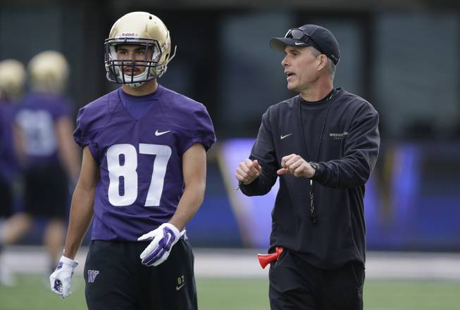 Washington head coach Chris Petersen, right, talks with wide receiver Dante Pettis, left, during NCAA college football practice drills, Monday, March 30, 2015, on the first day of spring practice in Seattle.