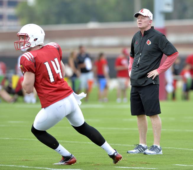 Louisville head coach Bobby Petrino, right, looks on as sophomore quarterback Kyle Bolin participates in drills at the Louisville football practice facility in Louisville, Ky., Saturday, Aug. 8, 2015.