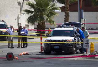 Investigators look into a Metro Police patrol vehicle after an officer in the vehicle was shot at the intersection of Tropicana Avenue and Nellis Boulevard Sunday, Sept. 6, 2015. A pedestrian approached the vehicle and fired from a handgun, striking the officer in the hand, police said.