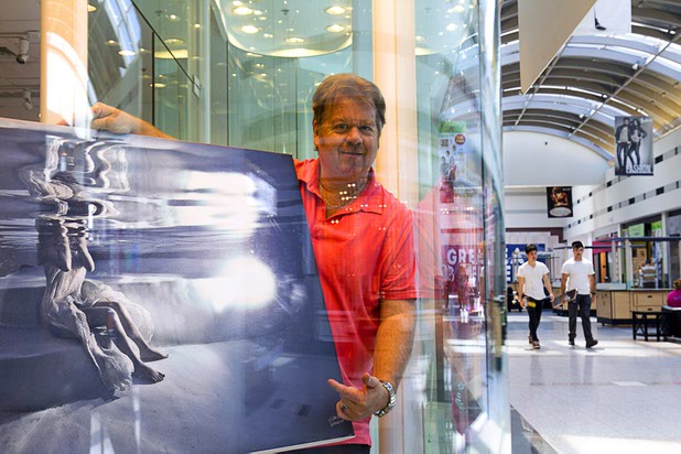Photographer Shaun Goodrich poses with one of his works in The Art Photographers, a photo gallery and studio, in the Boulevard Mall Sunday, Sept. 6, 2015. Goodrich operates the gallery with partner James Hickey.