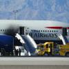 Firefighters stand by a British Airways plane that caught fire Tuesday, Sept. 8, 2015, at McCarran International Airport. An engine on the plane caught fire before takeoff, forcing passengers to escape on emergency slides.