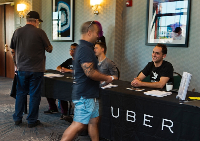 Uber workers welcome and instruct applicants on their next steps through the process at the Uber Activation Center at Hampton Inn Tropicana on Wednesday, September 16, 2015.