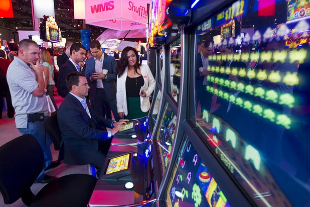 People try out the Space Invaders slot machine by Scientific Games during the Global Gaming Expo (G2E) at the Sands Expo Center Tuesday, Sept. 29, 2015. The slots include a skill-based bonus round.
