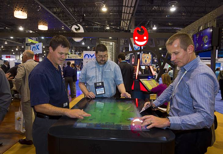 Harlan Darrah, left, Kevin Johnson, center, and Adam Jacobs play a skill-based table-top game at the Gamblit booth during the second day of the Global Gaming Expo (G2E) in the Sands Expo Center Wednesday, Sept. 30, 2015.