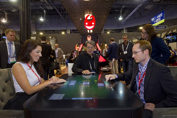 Mackenzi Bovero, left, Steven Buechler, and Daniel Dianni play a interactive table-top poker game at the Gamblit booth during the second day of the Global Gaming Expo (G2E) in the Sands Expo Center Wednesday, Sept. 30, 2015.