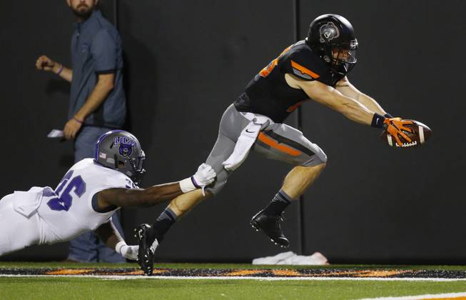 Oklahoma State wide receiver David Glidden, front right, avoids a tackle by Central Arkansas defensive back Brandon Porter (36) to begin his dive into the end zone for a touchdown in the fourth quarter of an NCAA college football game in Stillwater, Okla., Saturday, Sept. 12, 2015. 