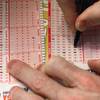 In this March 29, 2012, file photo, a customer fills out a lottery form for the Mega Millions drawing in Chicago. Illinois Lottery ticket sales have plummeted since lottery officials announced delaying payouts over $600 because of the state budget impasse.
