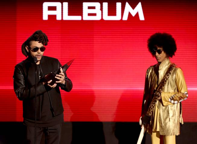 The Weeknd accepts an award from Prince during the American Music Awards at Microsoft Theater on Sunday, Nov. 22, 2015, in Los Angeles.
