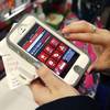 In this Friday, Nov. 23, 2012, file photo, Tashalee Rodriguez, of Boston, uses a smartphone app while shopping at Macy's in downtown Boston.
