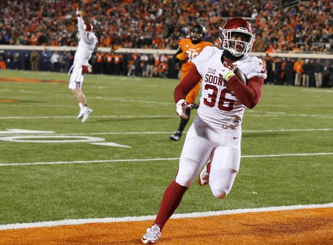 Oklahoma fullback Dimitri Flowers (36) scores in front of Oklahoma State defensive end Trace Clark and Oklahoma quarterback Baker Mayfield, left.