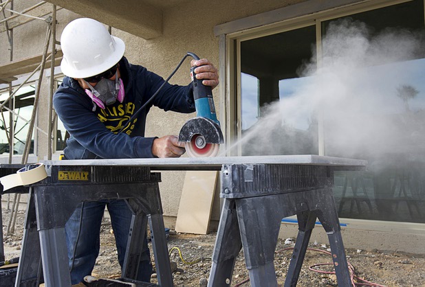 Delfino Barajas cuts a hole for a bathroom sink in a granite countertop during construction of model homes at The Estates at Rhodes Ranch, a Century Communities development, Thursday, Dec. 3, 2015.