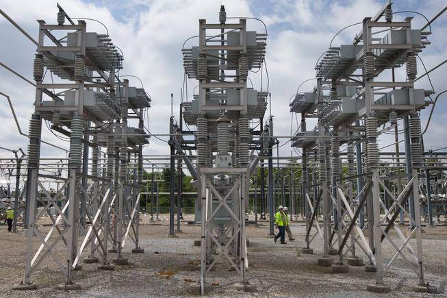Contractors walk past a capacitor bank at an AEP electrical transmission substation in Westerville, Ohio, on Wednesday, May 20, 2015.