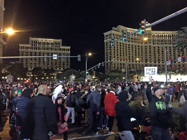New Year's Eve revelers are shown in front of the Bellagio, Thursday, Dec. 31, 2015. "Free Hugs" signs were given out for free nearby.