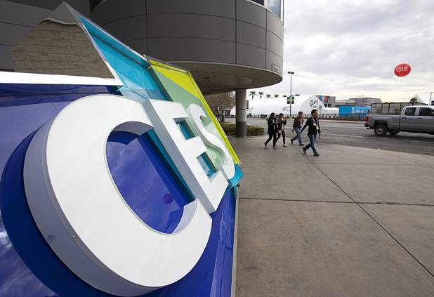 A group passes by a CES sign as workers prepare for the 2016 International CES at the Las Vegas Convention Center Sunday, Jan. 3, 2016. The trade show floor opens on Jan. 6.