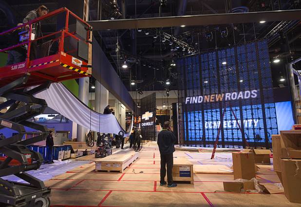 Workers hang a banner in a Chevrolet booth as they set up for the 2016 International CES at the Las Vegas Convention Center Sunday, Jan. 3, 2015. The trade show floor opens on Jan. 6.