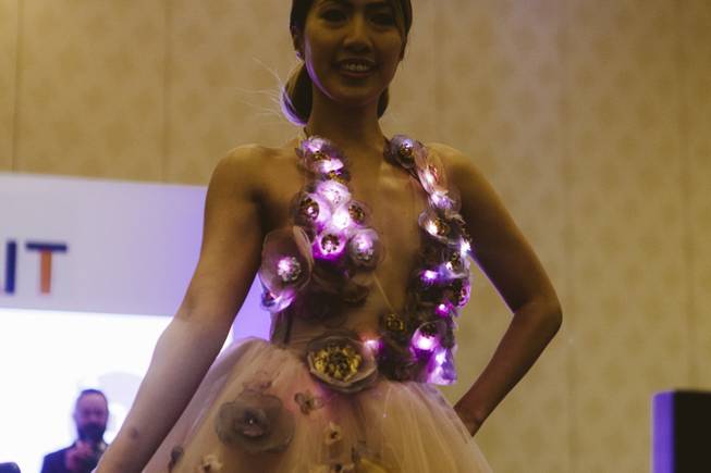 A model walks down the runway at a FashionWare show during CES at the Venetian on Jan. 7, 2016.  She is wearing a design by Maria Orduz in part with the Make Fashion Team. The Dress is decorated with a combination of handmade fabric flowers that deflect the light, and 3D printed flowers. The bottom of the skirt has optic fibers woven onto the skirt creating a seamless subtle lighting effect, that reacts to sound.