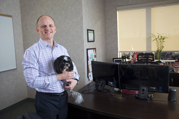 Jeff Grace, CEO of NetEffect, poses in his office with Rags, an eight-year-old Shih Tzu, Monday, Jan 11, 2016. 
